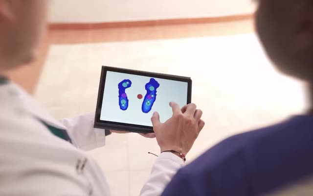 Podólogo y paciente miran el mapa de presión de la pisada en una tablet.