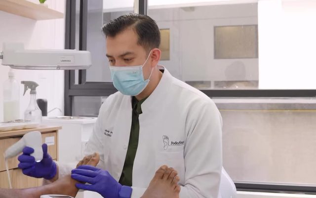 Iván Pérez evaluando el pie de un paciente en la consulta de PodoFeet.